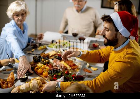 Glückliche Familie mit mehreren Generationen, die zu Hause das neue Jahr am Tisch feiert Stockfoto