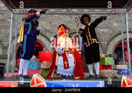 ENSCHEDE, NIEDERLANDE - 13. NOV 2021: Der niederländische Weihnachtsmann namens Sinterklaas kommt in die Stadt. In diesem Jahr sitzt er auf einem Stuhl davor Stockfoto