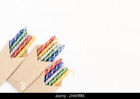 Mehrfarbige Glitzernde Golden Yellow, Red, Blue Und Green Kerzen Verpackt In Braunem Craft Paper Diagonal Platziert. Isoliert Auf Weißem Hintergrund Mit Cop Stockfoto