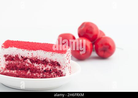 Frischer Roter Samtpastkuchen, Serviert Auf Teller Mit Kirschen Im Hintergrund. Isoliert Auf Weißem Hintergrund Mit Kopieren Oder Negativem Abstand Für Benutzerdefinierten Text Stockfoto