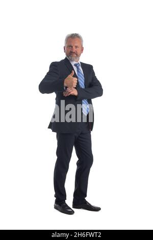 In voller Länge Porträt eines lächelnden Geschäftsmanns, der den Daumen hochgibt und eine Hand in die Anzugtasche hält, isoliert auf weißem Hintergrund Stockfoto
