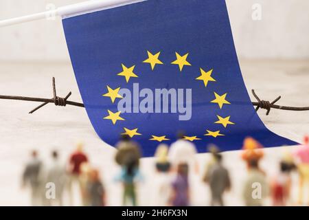 EU-Flagge, Stacheldraht und Plastikspielzeugmänner außer Fokus, Konzept der illegalen Migration in die Europäische Union Stockfoto