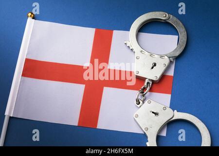England Kreuz von St. George Rote Weiße Flagge und Handschellen auf blauem Hintergrund, Krimikonzept Stockfoto