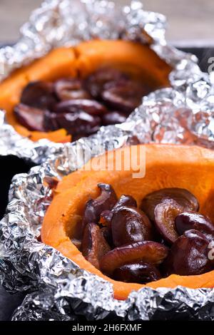 Hokkaido Kürbishälften in Folie gebacken, gefüllt mit Pflaumen auf einem Backblech. Vegetarische Gerichte. Die ketogene Ernährung. Veganes Paleo Stockfoto