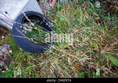 Gebrauchte Reifen wurden illegal am Straßenrand in einer ruhigen Gasse in der Nähe von Halifax, Calderdale, West Yorkshire, abgeladen. Fliegenkippen ist eine schwere Straftat, die eine Geldstrafe von bis zu £50,000 (unbegrenzt, wenn der Fall an das Crown Court geht) mit sich bringt, oder ein Täter kann sogar ins Gefängnis geschickt werden. Stockfoto