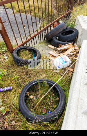 Gebrauchte Reifen wurden illegal am Straßenrand in einer ruhigen Gasse in der Nähe von Halifax, Calderdale, West Yorkshire, abgeladen. Fliegenkippen ist eine schwere Straftat, die eine Geldstrafe von bis zu £50,000 (unbegrenzt, wenn der Fall an das Crown Court geht) mit sich bringt, oder ein Täter kann sogar ins Gefängnis geschickt werden. Stockfoto