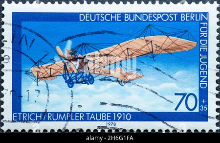DEUTSCHLAND, Berlin - UM 1978: Eine Briefmarke aus Deutschland, Berlin zeigt ein historisches Motorflugzeug mit Propeller Text: Etrich Rumpler Taube 1910 Stockfoto