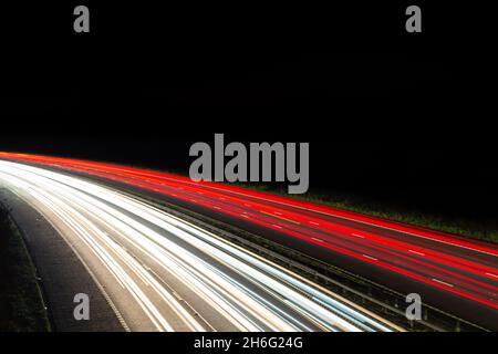 Nachts werden leichte Wege von einer verkehrsreichen Autobahn oder Autobahn angezeigt, die die Verkehrsbewegungen während der Hauptverkehrszeit zeigen. Großer leerer Bereich mit Platz für Text Stockfoto