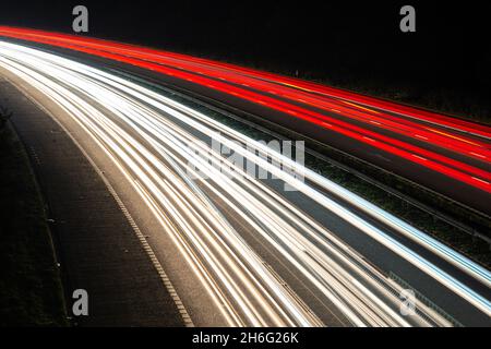 Nachts werden leichte Wege von einer verkehrsreichen Autobahn oder Autobahn angezeigt, die die Verkehrsbewegungen während der Hauptverkehrszeit zeigen. Der Verkehr scheint auf der rechten Seite zu liegen Stockfoto