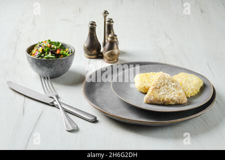 Halbfertiger Tintenfisch-Schnitzel in der Panade auf einem Teller Stockfoto