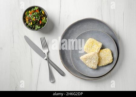 Draufsicht des halbfertigen Tintenfisch-Schnittes in der Panade auf einer Platte Stockfoto