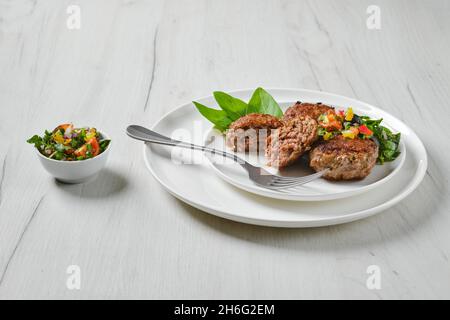 Gebratene Fleischbällchen auf einem Teller mit Basilikum und Tomaten Stockfoto