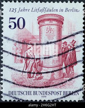 DEUTSCHLAND, Berlin - UM 1980: Eine Briefmarke aus Deutschland, Berlin mit einer historischen Werbespalte mit Publikum. Text: 125 Jahre Werbung Stockfoto