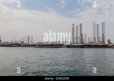 Boote, Ölabstürze und Kraniche im Hafen von Khalid in Sharjah, Vereinigte Arabische Emirate. Stockfoto