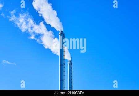 Zwei Metallkamine mit weißem Rauch am klaren blauen Himmel. Hochwertige Fotos Stockfoto