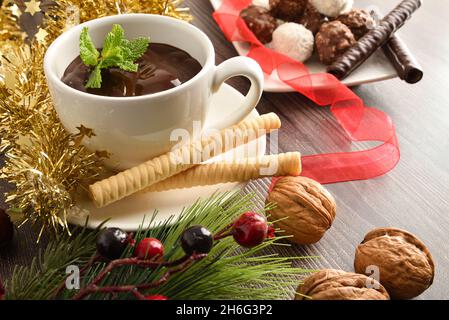 Detail von heißer Schokolade mit Waffeln auf Weihnachten dekorierten Tisch mit Süßigkeiten im Hintergrund. Erhöhte Ansicht. Horizontale Zusammensetzung. Stockfoto