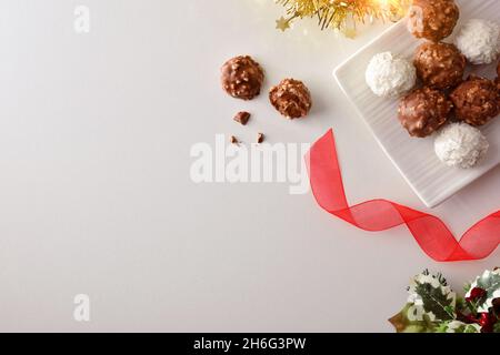 Süße Kugeln für Weihnachts-Snack mit Schokolade und Mandelstücken und Kokosnuss auf weißem Tisch mit weihnachtlicher Dekoration. Draufsicht. Stockfoto