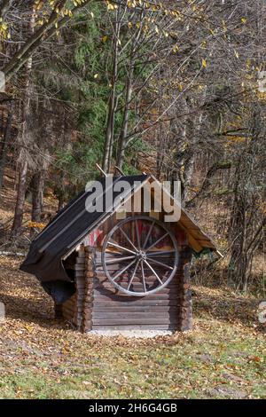 Ein altes hölzerner Waggonrad, das an der Wand einer Scheune hängt. Stockfoto