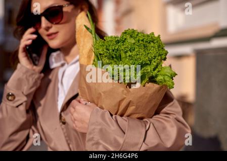 Öko Papierbeutel mit Lebensmitteln mit Brot und Gemüse in den Händen einer jungen Frau Stockfoto