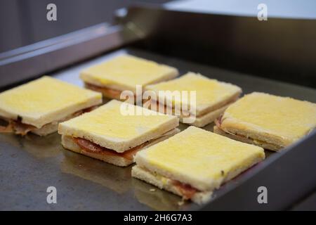 Gegrilltes und gepresstes Toast mit geräuchertem Schinken und Käse auf einem Tablett Stockfoto