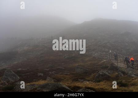 KARPACZ, POLEN - 16. OKTOBER 2021: Touristen besteigen den beliebten polnischen Berggipfel Sniezka im Riesengebirge bei bewölktem Wetter. Stockfoto