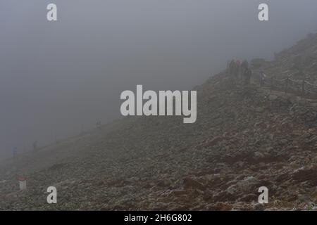 KARPACZ, POLEN - 16. OKTOBER 2021: Touristen besteigen den beliebten polnischen Berggipfel Sniezka im Riesengebirge bei bewölktem Wetter. Stockfoto