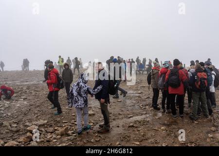 KARPACZ, POLEN - 16. OKTOBER 2021: Touristen auf dem Gipfel von Sniezka im Riesengebirge bei bewölktem Wetter. Stockfoto