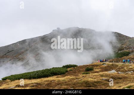 KARPACZ, POLEN - 16. OKTOBER 2021: Touristen besteigen den beliebten polnischen Berggipfel Sniezka im Riesengebirge bei bewölktem Wetter. Stockfoto