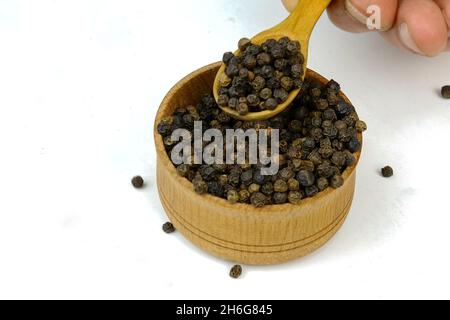 Koch nimmt trockene Gewürze schwarze Pfefferkörner und aus hölzernen Gewürzglas. Selektiver Fokus. Konzentrieren Sie sich auf Gewürze im Glas. Nahaufnahme. Stockfoto