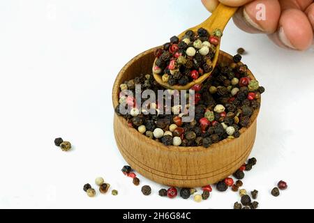 Koch nimmt trockene Gewürze Mischung aus verschiedenen farbigen Paprika Erbsen aus Holz Gewürzglas. Selektiver Fokus. Konzentrieren Sie sich auf Gewürze im Glas. Nahaufnahme. Stockfoto