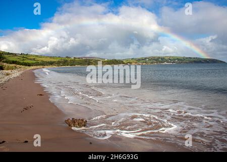 Redbay Castle unter einem Regenbogen am Waterfoot Beach, Co. Antrim, Nordirland Stockfoto