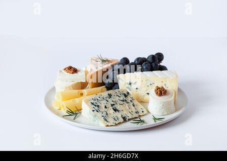Käseplatte serviert mit Trauben und Walnüssen auf grauem Betonboden Stockfoto
