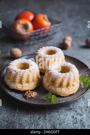 Mini-Kaki und Walnussgebundener Kuchen mit Puderzucker übersät Stockfoto