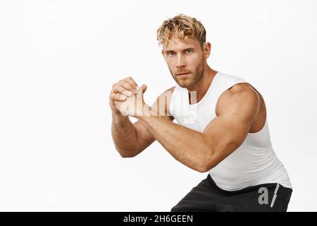 Bild eines gutaussehenden männlichen Sportlers, der Kniebeugen macht, Training im Fitnessstudio, Beinübungen, auf weißem Hintergrund stehend Stockfoto