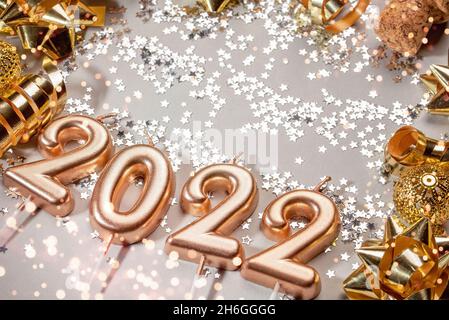 Urlaub Hintergrund Frohes neues Jahr 2021. Zahlen des Jahres 2022 von goldenen Kerzen auf Bokeh festlich funkelnden Hintergrund. Feiern Neujahr, Nahaufnahme. Platz für Text Stockfoto