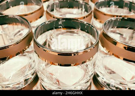 Viele Klarglas-Becher. Herstellung von Glaswaren. Leere Gläser mit dekorativen Rändern im Werk. Verkauf von Geschirr im Laden. Stockfoto