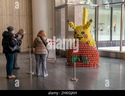 Besucher sehen, wie Pikachu beim jährlichen Canstruction Design Competition in New York, der am Sonntag, dem 7. November 2021, im Brookfield Place in New York zu sehen ist, einen Happen aus dem Big Apple von Microdesk nimmt. Architektur- und Designunternehmen beteiligen sich an der Planung und dem Bau riesiger Strukturen aus Dosen von Lebensmitteln. Die Dosen werden am Ende der Ausstellung an City Harvest gespendet. Über 100,000 Dosen Lebensmittel werden gesammelt und zur Versorgung der Bedürftigen in Suppenküchen und Speisekammern verwendet. (© Richard B. Levine) Stockfoto