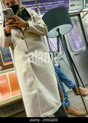 Die Reiterin hat sich am Sonntag, 7. November 2021, in der U-Bahn in New York mit ihrem Smartphone vertieft. (© Frances M. roberts) Stockfoto