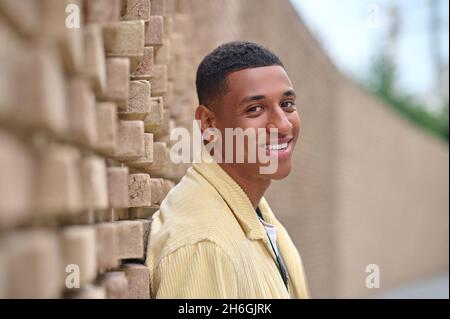 Kopfschuss eines jungen dunkelhäutigen Mannes in beiger Jacke Stockfoto