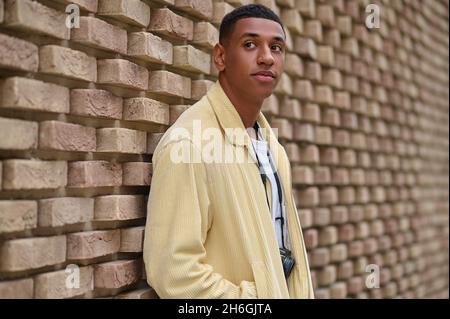 Kopfschuss eines jungen dunkelhäutigen Mannes in beiger Jacke Stockfoto