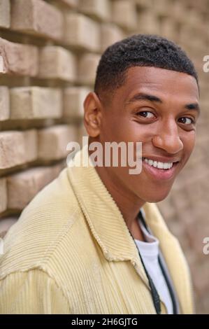 Kopfschuss eines jungen dunkelhäutigen Mannes in beiger Jacke Stockfoto