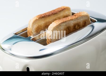 Zum Frühstück werden Scheiben Brot zubereitet. Der Toaster hat zwei knusprige Toasts. Stockfoto