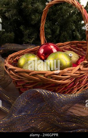 Korbkorb mit Kugeln, einige Kugeln mit Glitzer und blauem Zierband um, Dekorationen für Weihnachten im Studio, schöne Objekte Stockfoto