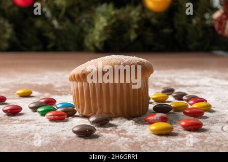 Köstlicher Cupcake, umgeben von verschiedenen runden Schokoladen mit bestreutem Zucker auf einem Tisch, Studio mit Essen, Desserts zu weihnachten Stockfoto