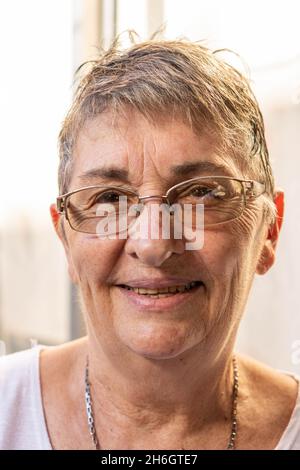 Nahaufnahme einer älteren Frau, die mit einer Brille lächelt. Stockfoto
