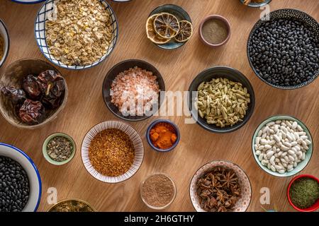 Set von Schüsseln mit Zutaten für Fusion Food Rezepte. Schwarze Bohnen, Sternanise, Reis, Chia und Kakao, Sternanise, Schwarzer Pfeffer, Panela Stockfoto