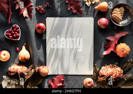 Orangefarbene Chrysanthemenblüten, trockenes Hasenschwanzgras und rote Eichenblätter, Kürbisse, Cranberry. Herbstschmuck, flach auf dunklem Textil. Stockfoto