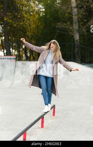 Junge blonde Mutter und kleiner Sohn auf einem Roller spielen zusammen auf einem Spielplatz Stockfoto