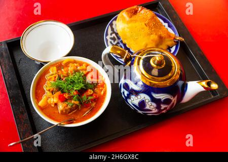 Usbekische Suppe laghman serviert mit samsa Stockfoto