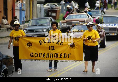 Austin, Texas, USA, um 1988: Frauen, die an der jährlichen Junienth-Parade teilnehmen, halten ein Banner für ihre Geschäftsgruppe Schwarze in der Regierung. ©Bob Daemmrich Stockfoto